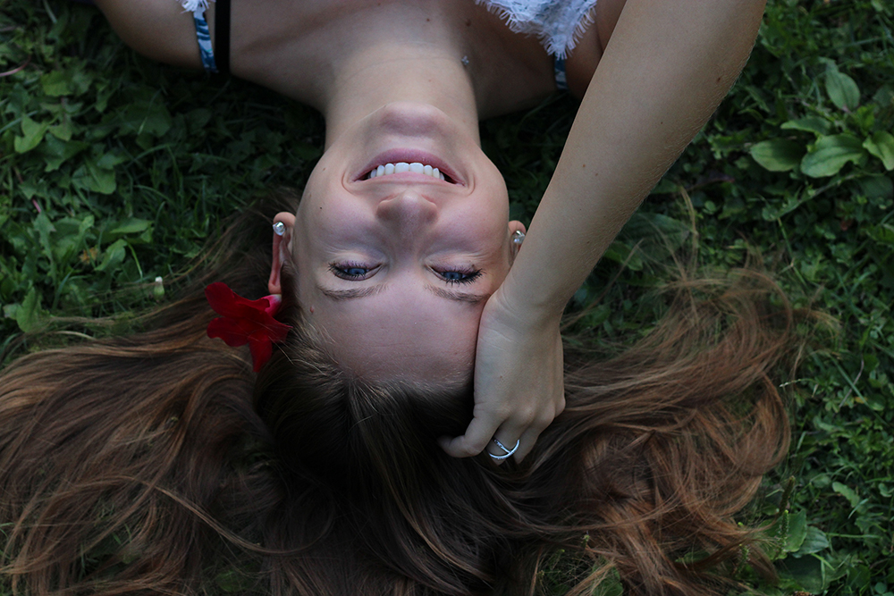 Portrait d'une femme brune souriante allongée dans l'heure avec une fleur dans les cheveux