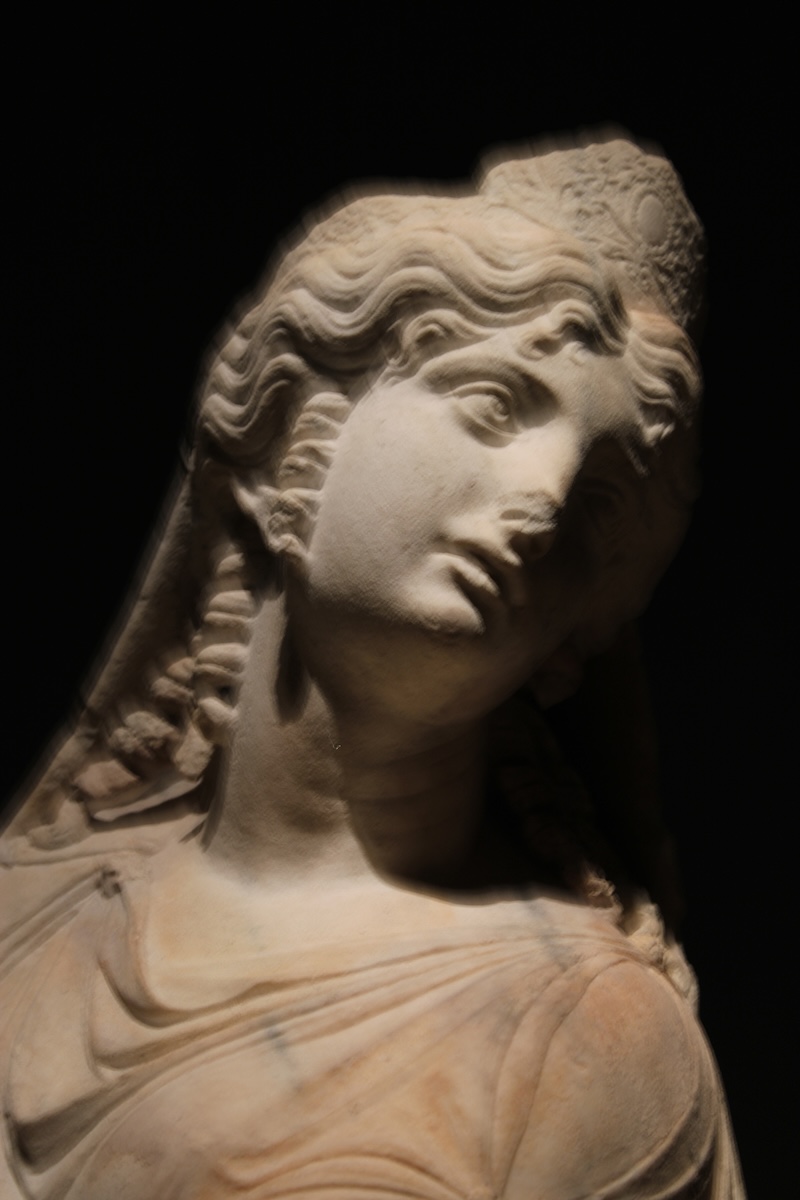 Photographie d'une statue en marbre de l'Avé Maria sur un fond noir, effet de flou autour de la statue