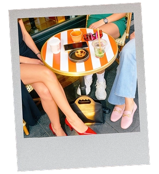 Polaroid de 3 amies assis sur une terrasse avec des boissons fraîches et un sac à main en synderme sous la table